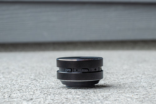 Black camera lens on a textured surface with a neutral background